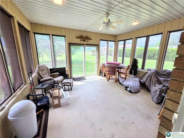 sunroom / solarium with a ceiling fan and wooden walls