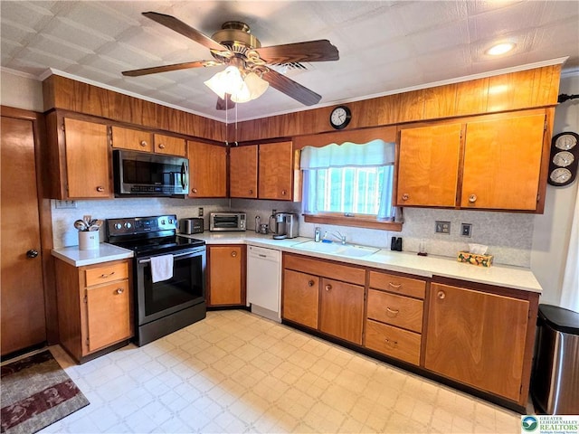 kitchen featuring appliances with stainless steel finishes, a sink, brown cabinets, light countertops, and ornamental molding
