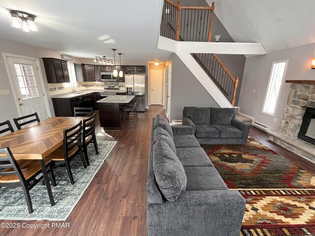 living room featuring a baseboard radiator, a stone fireplace, sink, and dark hardwood / wood-style flooring