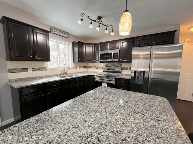 kitchen featuring appliances with stainless steel finishes, sink, decorative backsplash, and decorative light fixtures