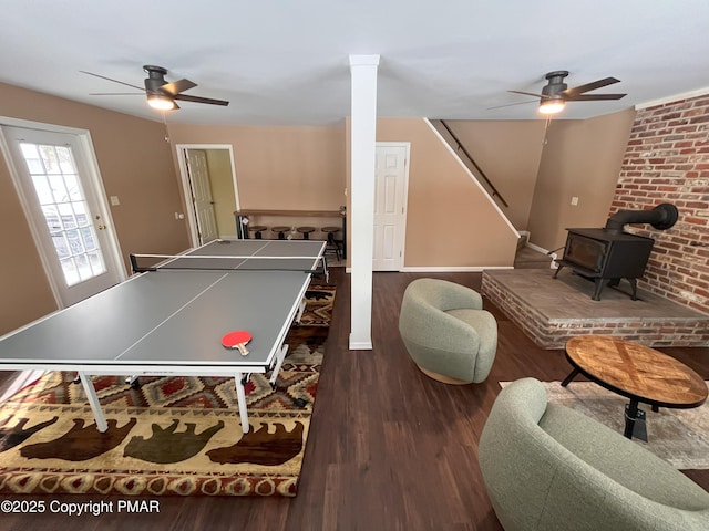 recreation room with ceiling fan, a wood stove, and dark hardwood / wood-style flooring