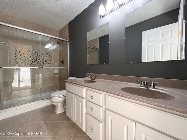 bathroom featuring an enclosed shower, vanity, a textured ceiling, tile patterned floors, and toilet