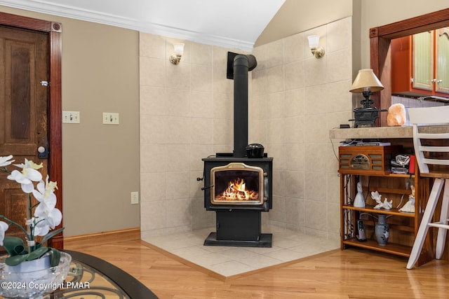 room details featuring wood finished floors, a wood stove, and crown molding