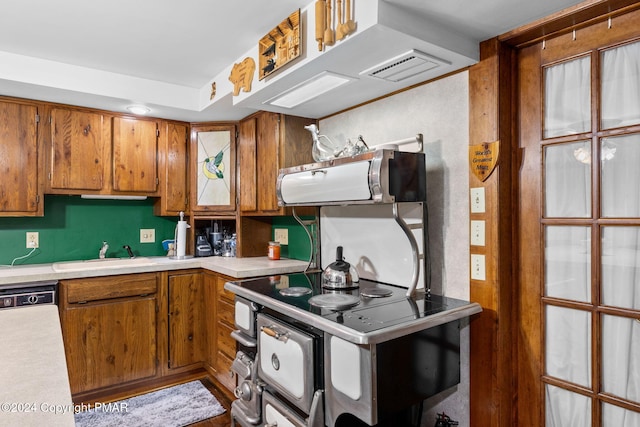 kitchen featuring dishwashing machine, brown cabinetry, a sink, extractor fan, and light countertops