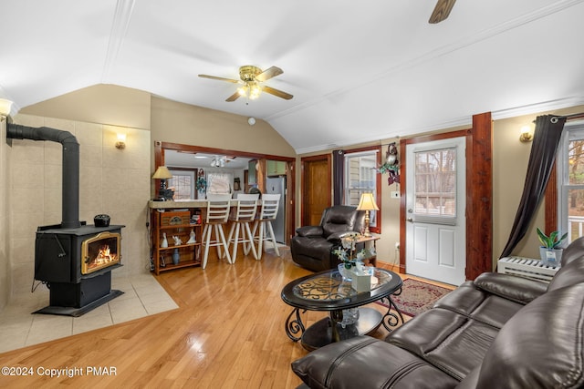 living area featuring wood finished floors, a wood stove, a ceiling fan, and vaulted ceiling