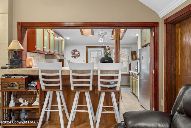 kitchen with a ceiling fan, tasteful backsplash, freestanding refrigerator, a peninsula, and light countertops