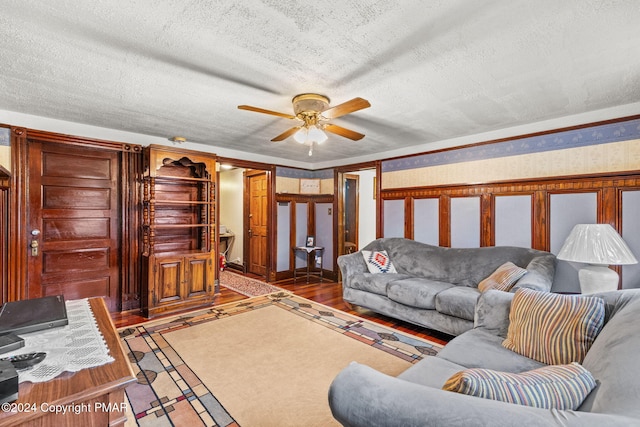 living area featuring a textured ceiling, wood finished floors, a ceiling fan, and wallpapered walls