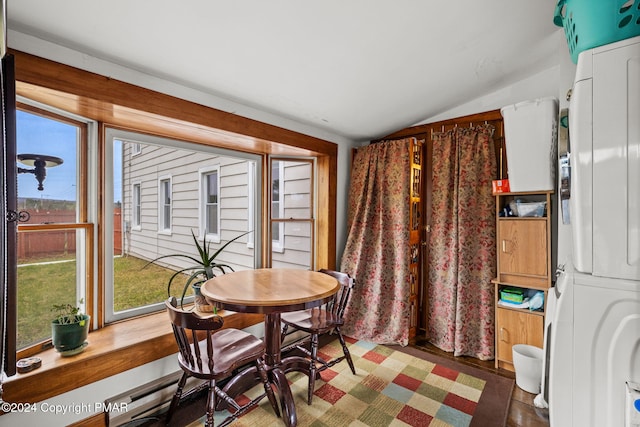 dining space with vaulted ceiling, stacked washer / dryer, and a wealth of natural light