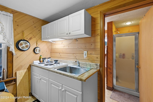 kitchen featuring light countertops, white cabinets, white electric stovetop, and a sink