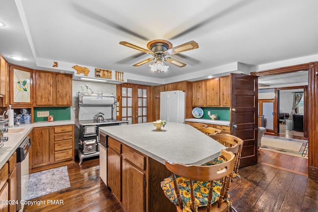 kitchen featuring dark wood-style floors, brown cabinets, freestanding refrigerator, and stainless steel dishwasher