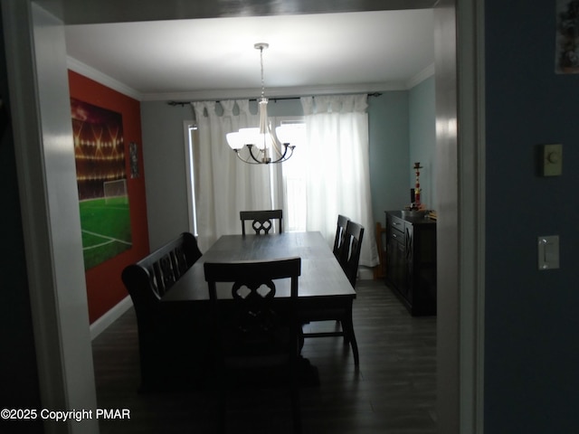 dining space with baseboards, ornamental molding, wood finished floors, and an inviting chandelier