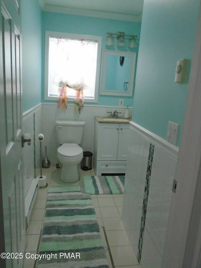 half bathroom featuring ornamental molding, tile patterned flooring, wainscoting, and toilet