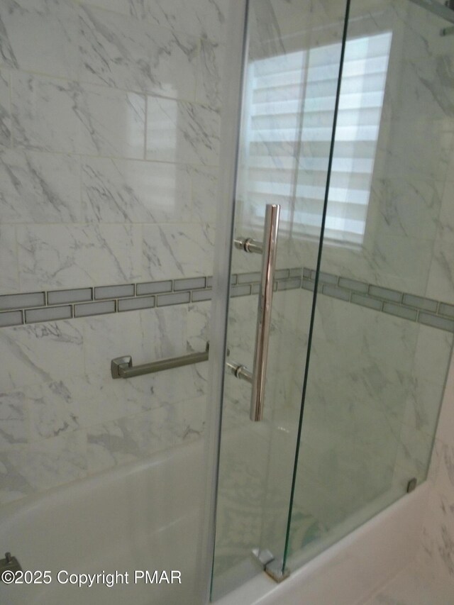 bathroom featuring combined bath / shower with glass door