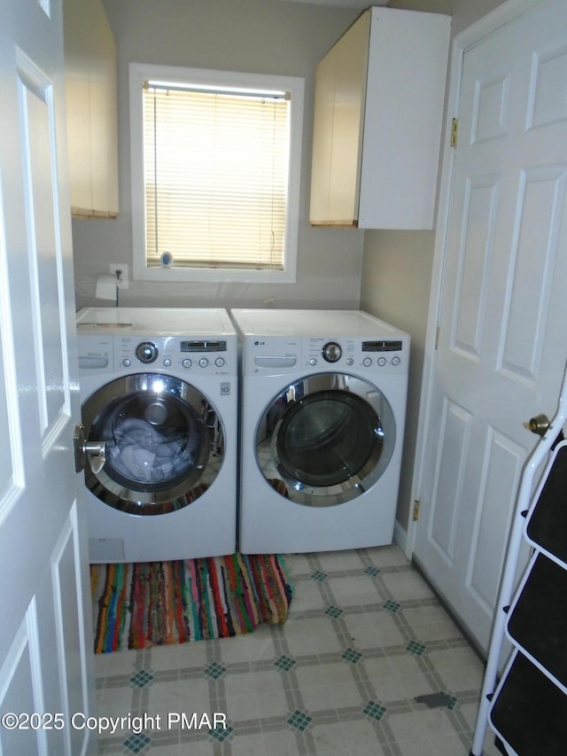 washroom featuring light floors, cabinet space, and washer and dryer