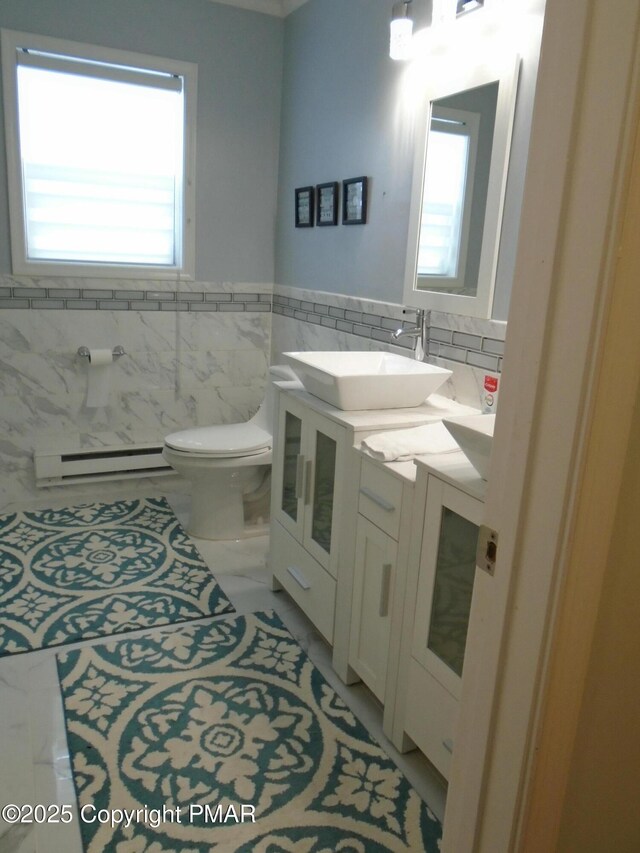 bathroom with vanity, a wealth of natural light, baseboard heating, and toilet