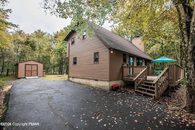 view of home's exterior with a deck, an outdoor structure, crawl space, a shed, and a chimney