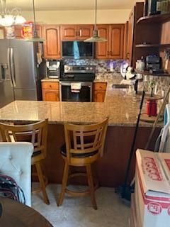 60 Arbutus Ln, East Stroudsburg, PA 18302 - kitchen featuring stainless steel appliances, a peninsula, brown cabinetry, and a kitchen breakfast bar
