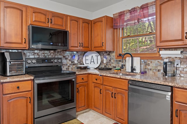 60 Arbutus Ln, East Stroudsburg, PA 18302 - kitchen with appliances with stainless steel finishes, brown cabinetry, light stone countertops, and backsplash