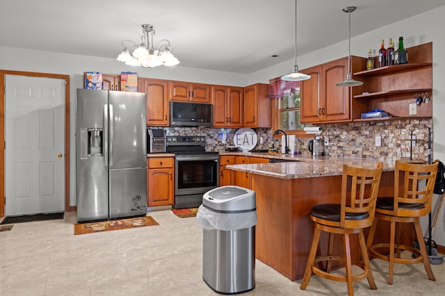 60 Arbutus Ln, East Stroudsburg, PA 18302 - kitchen with stainless steel appliances, brown cabinetry, a peninsula, tasteful backsplash, and a chandelier