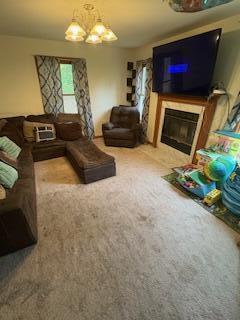 60 Arbutus Ln, East Stroudsburg, PA 18302 - living room with a glass covered fireplace, carpet, and a chandelier