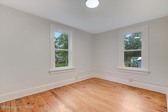 spare room featuring baseboards, wood finished floors, and plenty of natural light