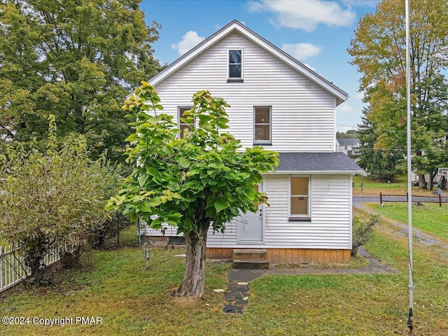back of house with a yard, entry steps, and roof with shingles
