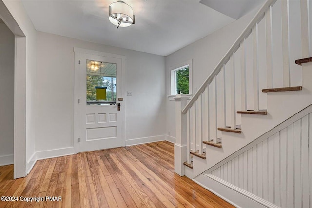 foyer featuring stairway, light wood finished floors, and baseboards