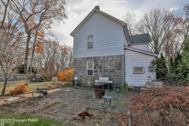 3310 Hazen Ave, Roseto, PA 18013 - back of house featuring a fire pit, stone siding, a shingled roof, and fence