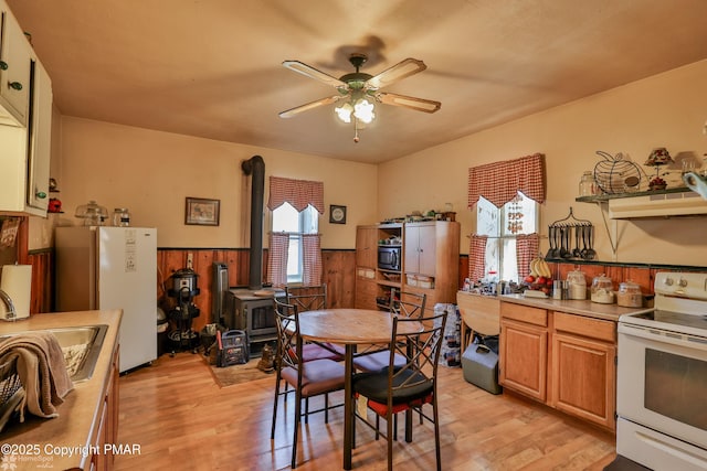 3310 Hazen Ave, Roseto, PA 18013 - dining space featuring a wainscoted wall, a wood stove, light wood-style flooring, and a ceiling fan