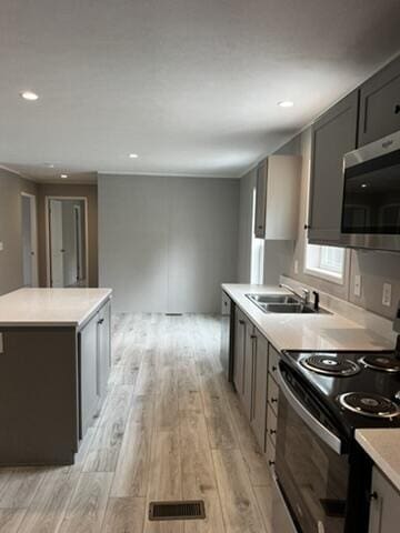 132 Spruce St, Greentown, PA 18426 - kitchen featuring black electric range oven, stainless steel microwave, a sink, light wood finished floors, and light countertops