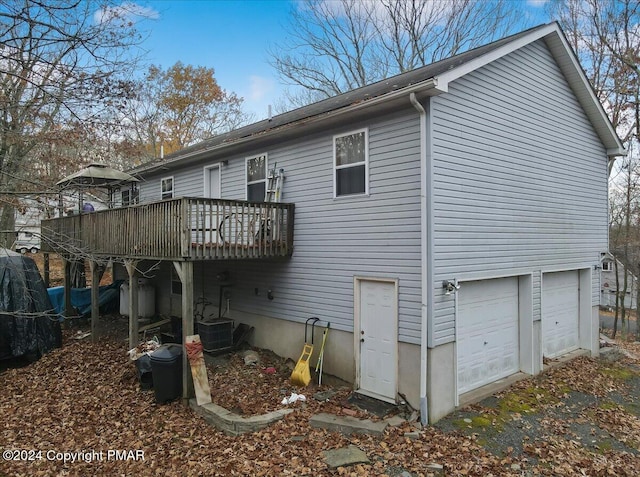 back of property with a wooden deck and an attached garage