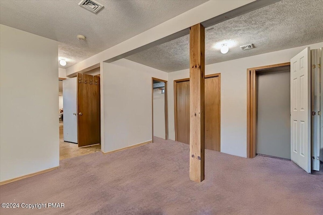 below grade area with carpet floors, visible vents, and a textured ceiling