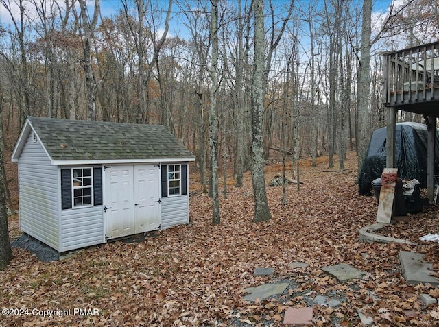 view of yard featuring a storage shed, an outdoor structure, and a wooded view