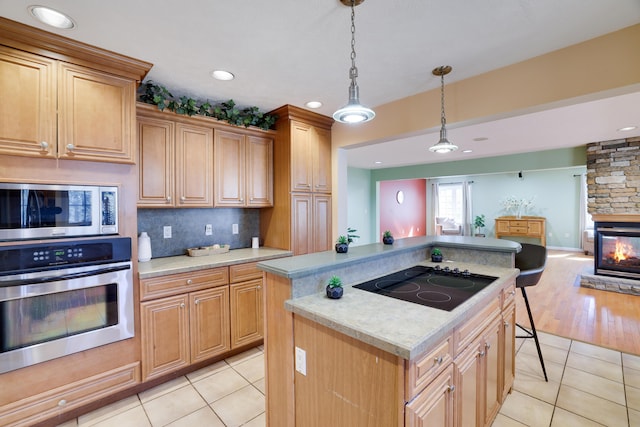 kitchen featuring light tile patterned floors, a kitchen island, appliances with stainless steel finishes, tasteful backsplash, and open floor plan
