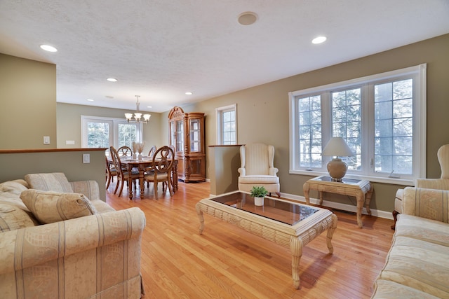 living area featuring a wealth of natural light, a notable chandelier, recessed lighting, and light wood-style floors