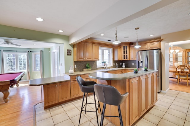 kitchen with a kitchen breakfast bar, tasteful backsplash, a kitchen island, a peninsula, and stainless steel fridge with ice dispenser