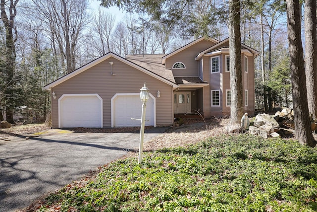 view of front facade featuring an attached garage, driveway, and a shingled roof