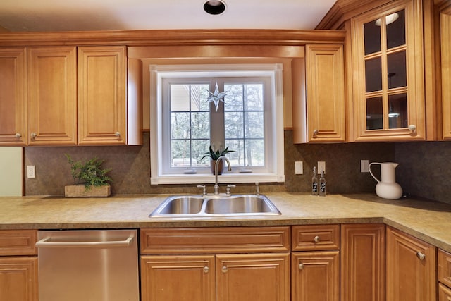 kitchen featuring dishwasher, glass insert cabinets, backsplash, and a sink