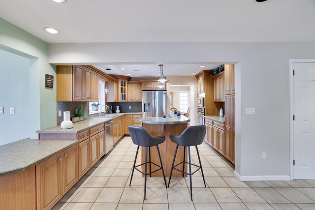kitchen featuring a center island, appliances with stainless steel finishes, light tile patterned flooring, a breakfast bar area, and decorative backsplash