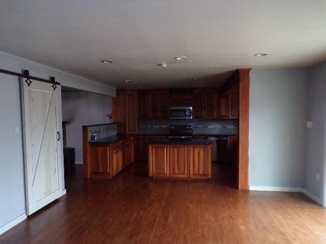 1292 Brentwood Dr, East Stroudsburg, PA 18301 - kitchen with stainless steel microwave, range with electric cooktop, a barn door, dark wood-style flooring, and baseboards
