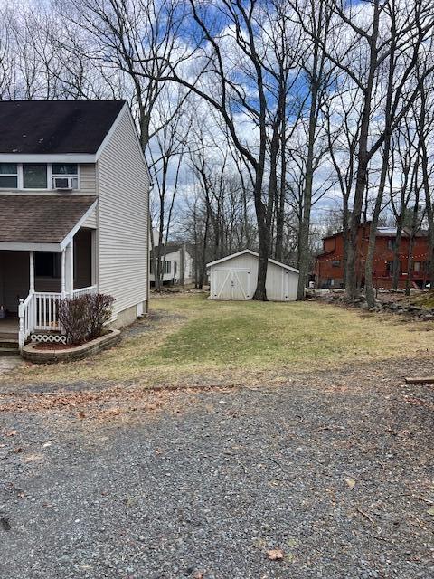 1292 Brentwood Dr, East Stroudsburg, PA 18301 - view of side of home featuring roof with shingles, a porch, and a lawn