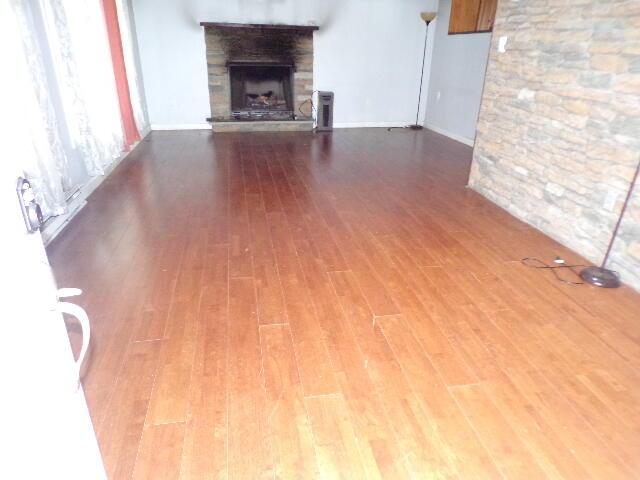 1292 Brentwood Dr, East Stroudsburg, PA 18301 - unfurnished living room featuring wood finished floors, a stone fireplace, and baseboards