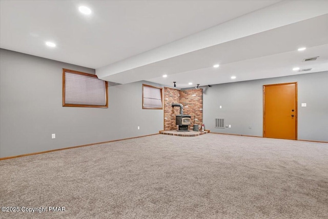 unfurnished living room featuring carpet and a wood stove