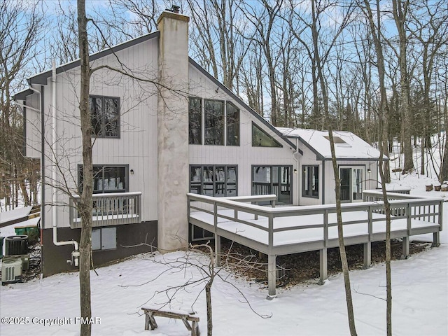 snow covered back of property with a wooden deck and central air condition unit