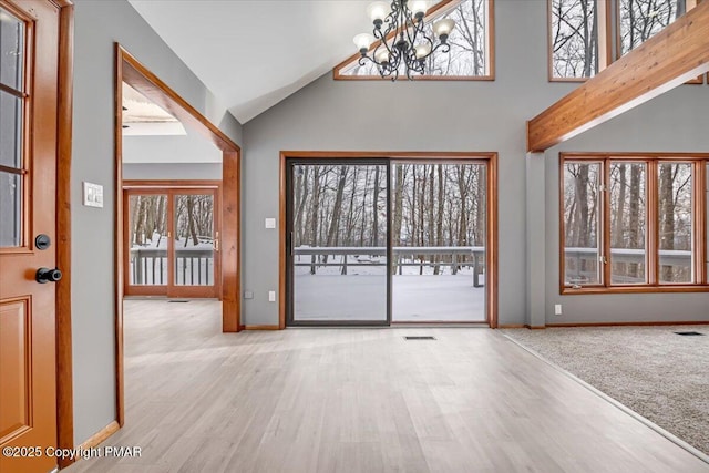 interior space featuring an inviting chandelier, light hardwood / wood-style flooring, and high vaulted ceiling