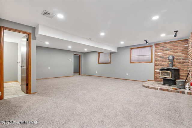 unfurnished living room with light colored carpet and a wood stove