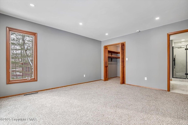 unfurnished bedroom with light carpet, a closet, and ensuite bathroom