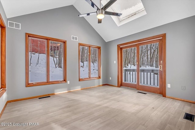 spare room with light hardwood / wood-style flooring, a skylight, high vaulted ceiling, and ceiling fan