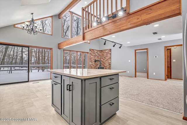 kitchen with gray cabinetry, beam ceiling, plenty of natural light, and a center island