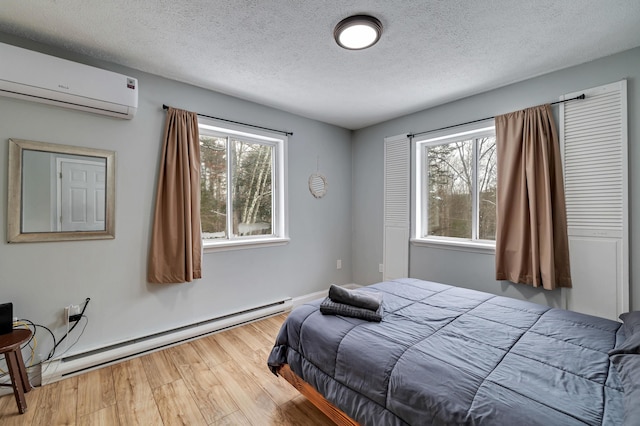 982 Long Ridge Rd, Hawley, PA 18428 - bedroom featuring a textured ceiling, wood finished floors, a wall unit AC, and baseboard heating